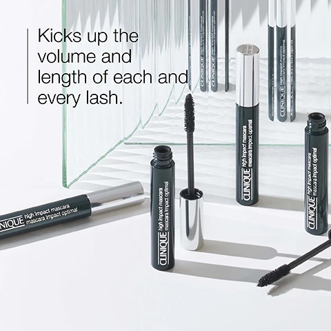 Image 1 - Image shows several tubes of Clinique High Impact Mascara arranged on a reflective surface with a tube open, and the text says Kicks up the volume and length of each and every lash.
Image 2 - A close-up image of a black mascara brush featuring a soft fibre bristle design, with visible text stating Soft fibre brush combs and defines and Buildable volume + length.
Image 3 - A close-up image of a persons eye with a mascara brush being applied, accompanied by text that reads The Clinique Eye Safety Promise. Hard-working makeup thats easy on the eyes. Ophthalmologist tested. Safe for sensitive eyes. Safe for contact lens wearers.