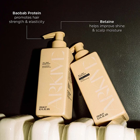 Image 6 - Two cream-colored Arkive hair care bottles with pump tops are shown, with text on the left bottle reading ALL DAY EVERYDAY SHAMPOO SHAMPOOING 250 mL e 8.5 FL. OZ. (US) and the right bottle reading ALL DAY EVERYDAY CONDITIONER APRÈS SHAMPOOING 250 mL e 8.5 FL. OZ. (US), while annotations highlight Baobab Protein promotes hair strength & elasticity and Betaine helps improve shine & scalp moisture. Image 7 - A hand with tattoos holds a peach-colored rectangular ARKIVE All Day Everyday Shampoo bottle with a pump dispenser, next to text that reads: HOW TO USE: Apply a grape-sized amount to damp hair and massage from roots to ends. Rinse thoroughly. Follow with All Day Everyday Conditioner. TOP TIPS: Comb through hair to detangle before beginning cleansing routine. For a moment of headcare, massage scalp with fingertips before thoroughly rinsing. The bottle label also includes SHAMPOOING BY ADAM REED 250 ml e 8.5 fl oz. Image 8 - A branch with small white flowers and green leaves is shown against a light background, with text reading SMELLS LIKE: FUTURE BLOOM A genderful floral fragrance that emulates a sun-soaked summer walk: liberating, luminous and full of potential. HEAD NOTES MANDARIN RHUBARB HEART NOTES JASMINE LILY OF THE VALLEY GROUND NOTES TEA ROSE VANILLA. Image 9 - Two light peach pump bottles, one shampoo and one conditioner, are surrounded by green leaves, orange slices, vanilla beans, and rose petals, featuring text Made Without: Aluminium Lactose Alcohol Mineral Oil Parabens Ammonia Silicone Sulphate Parabens Talc, with the shampoo bottle reading All Day Everyday Shampoo Shampooing 250 mL e 8.5 FL. OZ. (US) and the conditioner bottle reading All Day Everyday Conditioner Après Shampooing 250 mL e 8.5 FL. OZ. (US), alongside icons indicating Vegan, Certified B Corporation, Made with Recycled Content, Cruelty Free International, and Award Winning.