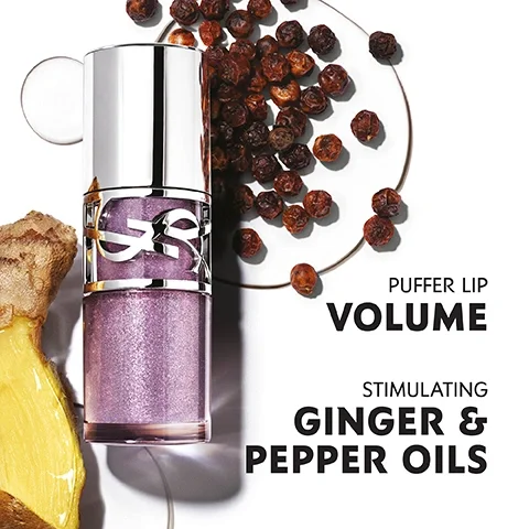 Image 1 - An opened lip gloss tube with a shimmering light purple color is displayed next to ginger root and dried berries on a white background, accompanied by the text Puffer Lip Volume and Stimulating Ginger & Pepper Oils.